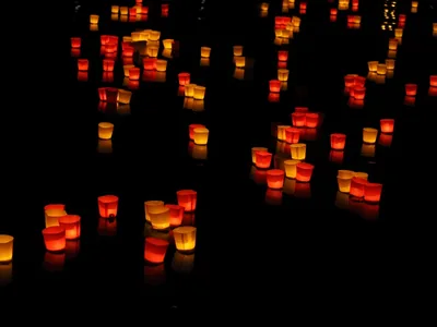 Many small lanterns glowing on dark water