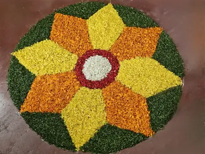 A round flower carpet of yellow and orange petals in a star pattern with a green border