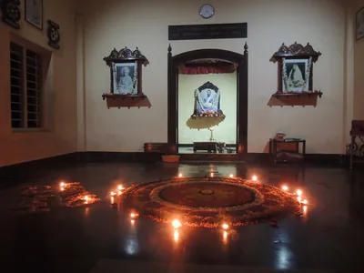 A flower carpet on a hall floor ringed by small burning oil lamps