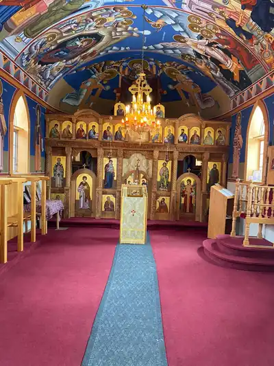 A golden icon screen and blue painted ceiling inside an Orthodox church