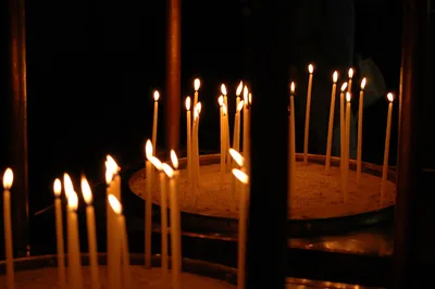 Thin beeswax candles burning in a dark church