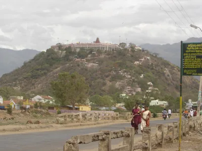 A hill with a temple on top, seen from the road below