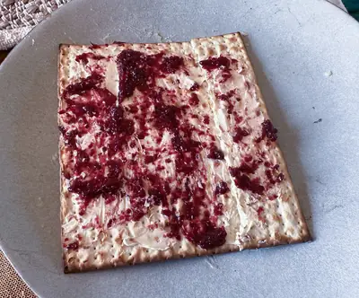 A sheet of matzah spread with red jam