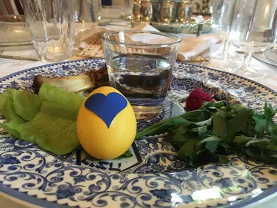 A blue patterned Seder plate with greens and matzah on the table
