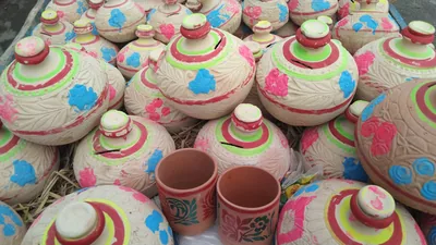 Hand-painted clay pots in pink, green and blue at a fair