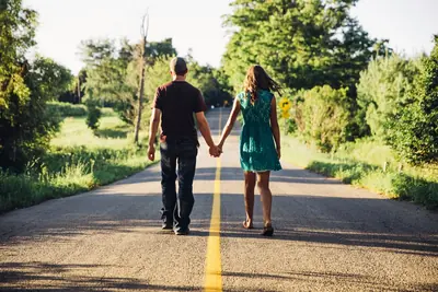 A couple walking hand in hand down a country road