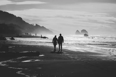 A couple walking hand in hand along a misty beach