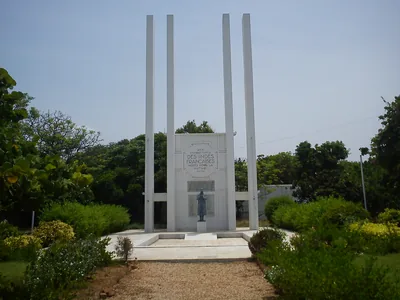 A white memorial with tall pillars in a green garden