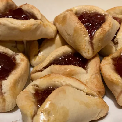 A plate of hamantaschen cookies filled with red jam