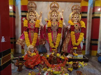 Decorated idols of Rama, Sita and Lakshmana with marigold garlands at a temple altar