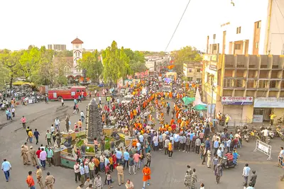 A large crowd fills a city street around a decorated float in a Ram Navami procession