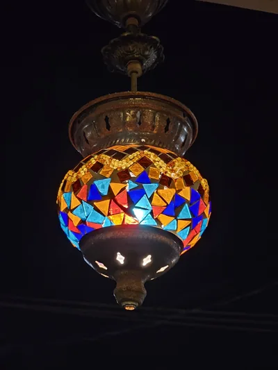 A glowing mosaic glass lantern hanging in the dark