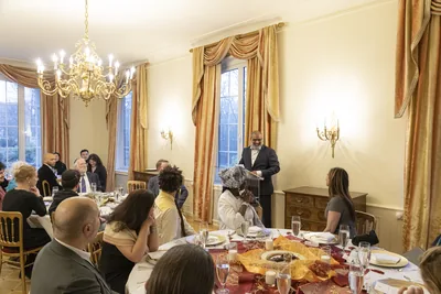 Guests sit at round tables for an iftar dinner in a large hall