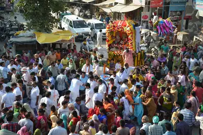 A crowd fills a street as a decorated chariot moves through it