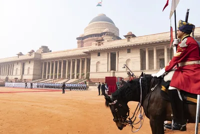 The domed sandstone front of Rashtrapati Bhavan with a mounted guard in the foreground