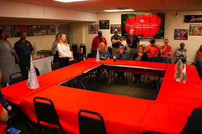 A room with red tables set in a square and a screen showing a happy retirement message
