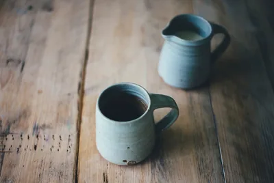 Two blue clay mugs on a wooden table