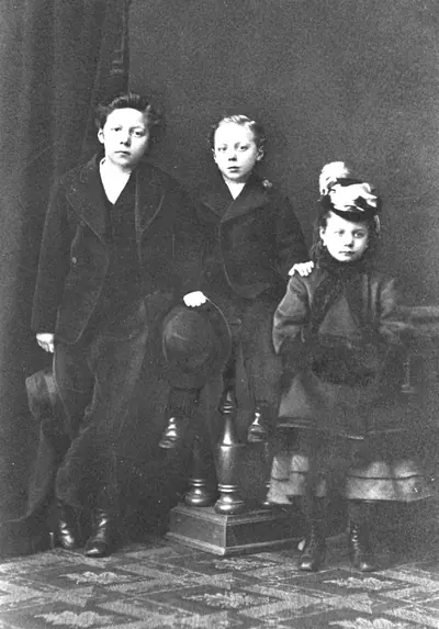 An old photo of three siblings in dark coats