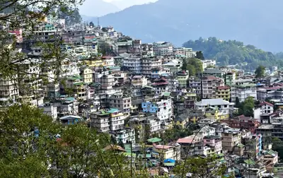 Colourful houses spread across a green hillside in Gangtok