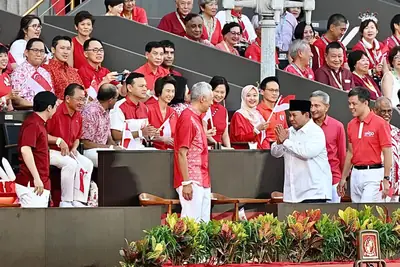 Rows of spectators dressed in red and white at the National Day Parade stands