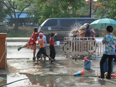 People splashing water at each other on a wet street