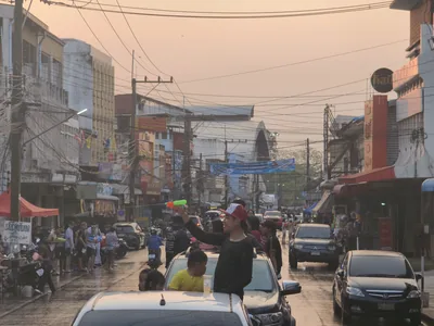 A busy street at dusk with people throwing water from cars and sidewalks