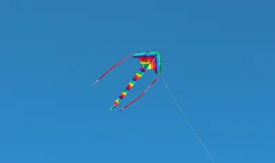 A bright kite flying high in a clear blue sky