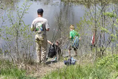 A father and his sons fishing at the edge of a lake, seen from behind