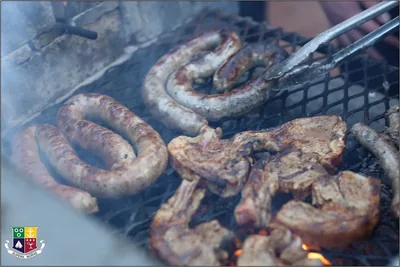Coils of boerewors sausage and meat cooking on a grill