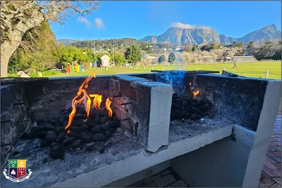 A fire burning in an outdoor brick braai with mountains behind