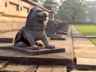 A row of carved stone lions along the base of a hall