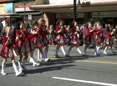 Young Irish dancers in red dresses dancing down a city street