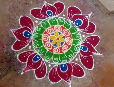 Bright rangoli of red, green and white petals around a yellow flower