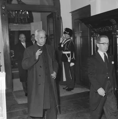 Black and white photo of Radhakrishnan in a long coat and white turban greeting officials