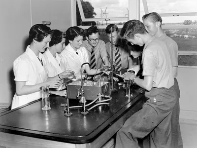 An old black and white photo of students doing experiments at a physics lab bench