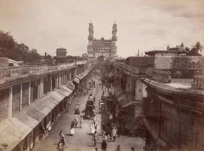 Old photo of a long street with shops leading to the Charminar