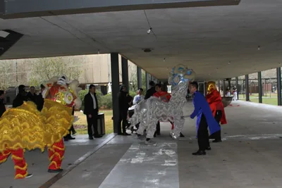 Lion and dragon dancers performing for a crowd under a covered hall