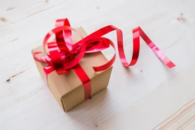A brown gift box tied with a red ribbon on white