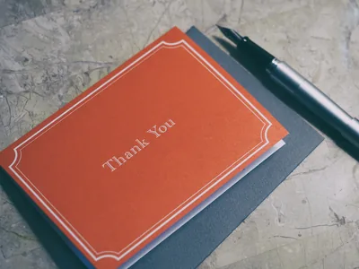 A red card that says thank you beside a pen
