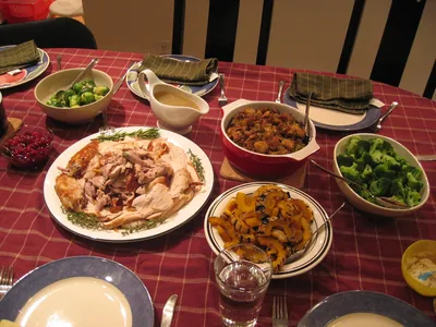 A table with roast turkey, vegetables, gravy and side dishes on a checked cloth