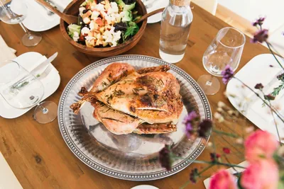 A roast turkey on a silver platter surrounded by salads and bread