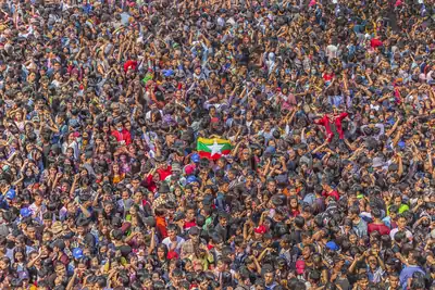 A huge crowd packed together with water spray and a Myanmar flag