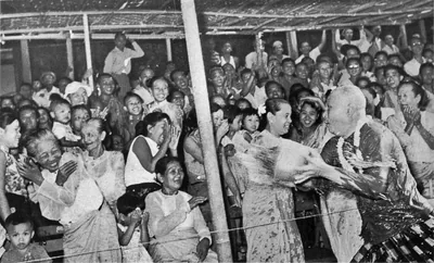 Old black and white photo of people laughing and throwing water under a shelter