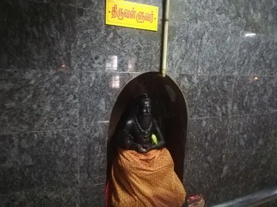 A small black statue of a seated sage in a stone shrine