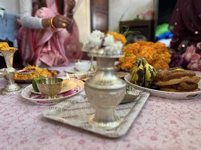 A table set with a brass vessel, marigolds, fruit and sweets for a family blessing