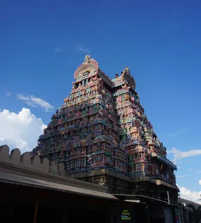 A tall painted temple tower in many colours under a blue sky
