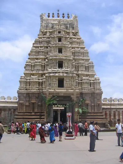 A carved stone temple tower with devotees gathered at the gate
