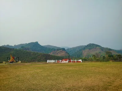 Green Meghalaya hills above a wide grass field