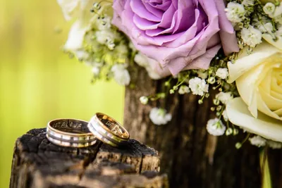 Two wedding rings beside lilac roses and small white flowers