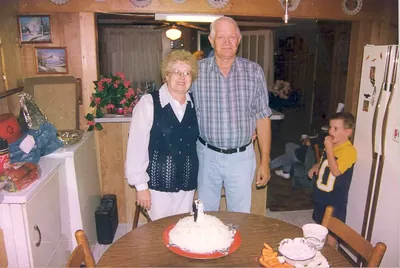 An older couple standing by a table with an anniversary cake